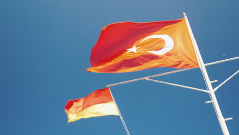 the turkish flag and the flag of the rescue service are fluttering against the blue sky safe rest co