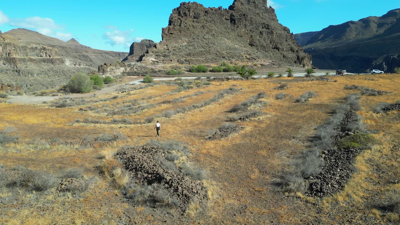 Ansite Fortress: Aerial view of woman walking through volcanic rocks on the island of Gran Canaria