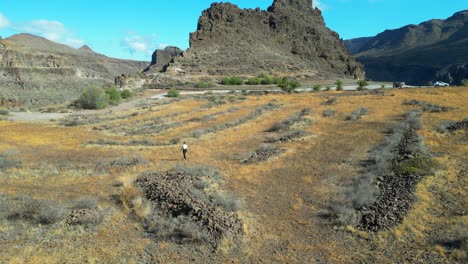 ansite fortress: aerial view of woman walking through volcanic rocks on the island of gran canaria