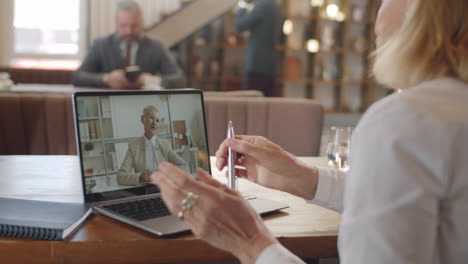 businesswoman talking with female colleague on web call in restaurant