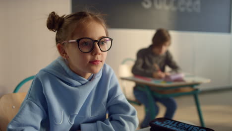 pupil sitting at school desk. cheerful child making notes in exercise book