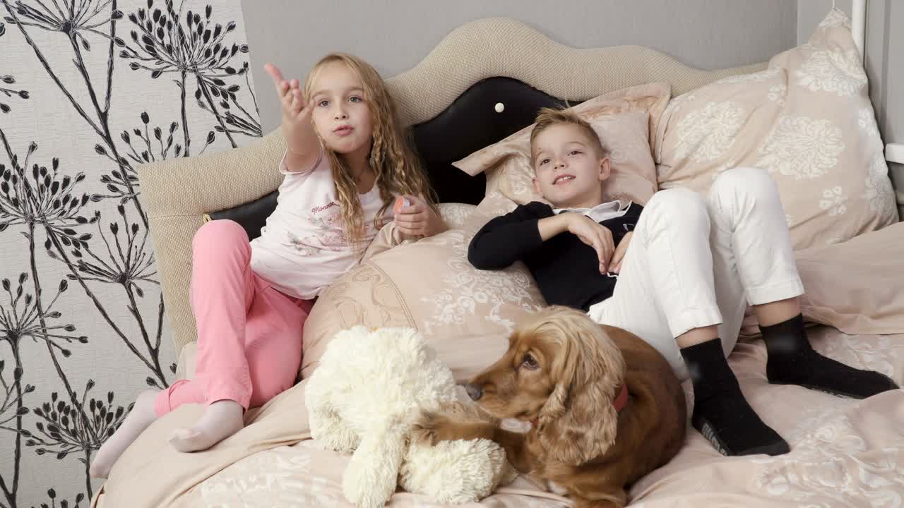 niños lindos miran la televisión, el perro se acuesta cerca de los niños