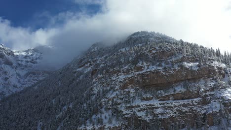 Aerial-view,-clouds-above-steep-snow-capped-hills-of-San-Juan-mountains-near-by-Ouray,-Colorado-USA