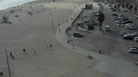 Antena:-Vuelo-Hacia-El-Skatepark-De-Venice-Beach-Y-Paseo-Marítimo-Con-Palmeras-Y-Carril-Bici,-Soleado,-Los-Angeles-California