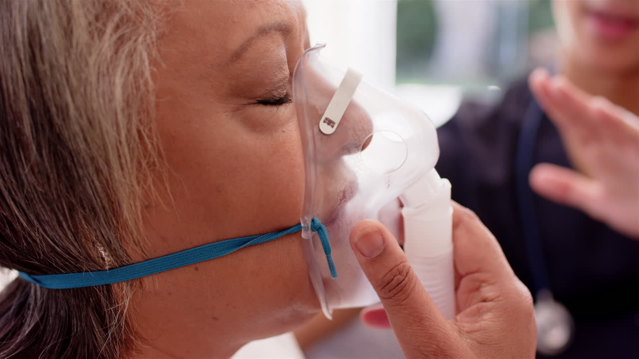 Using oxygen mask, senior woman assisted by male physiotherapist in healthcare setting