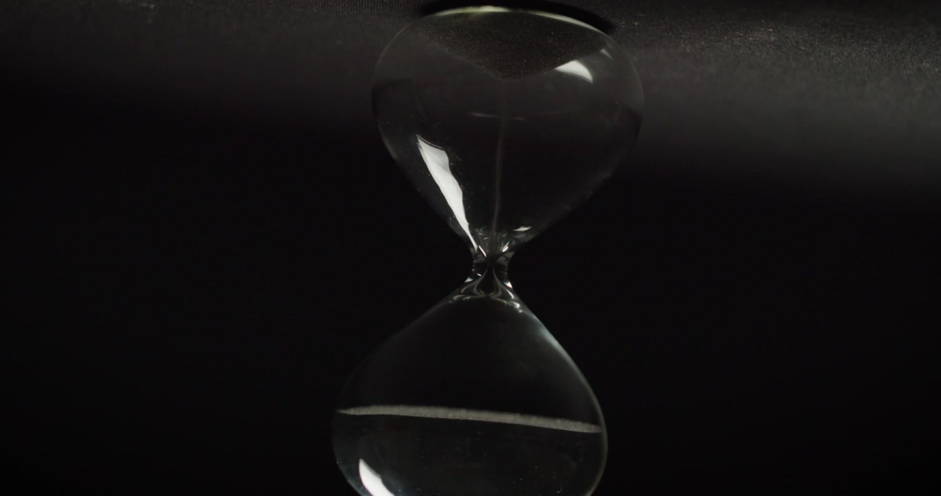 Sand clock rotating on black background