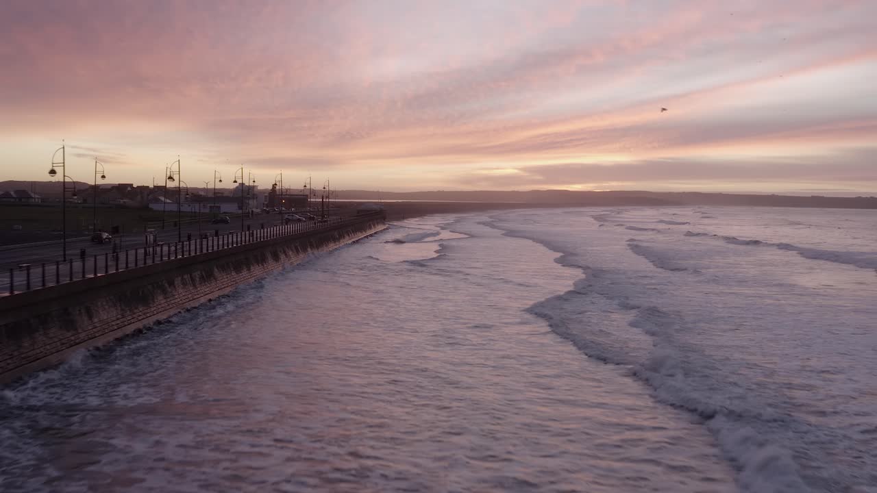 Waves reflect off seawall on Tramore Strand seaside at dawn sunrise