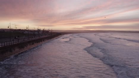 Wellen-Spiegeln-Sich-Bei-Sonnenaufgang-Am-Tramore-Strand-Am-Meer-Von-Der-Ufermauer-Wider