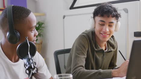 happy diverse male teenage friends using laptop and recording podcast, slow motion
