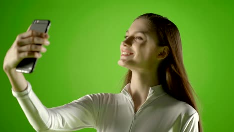 chica atractiva joven modelo de moda interactuar con su teléfono inteligente y tomar selfie pantalla verde prores disparar en ursa mini pro