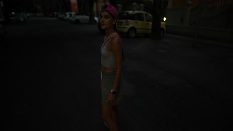 young woman walking down a city street at night