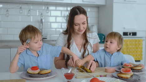 Beautiful-young-mother-with-two-children-sons-on-white-light-kuna-cook-with-burgers