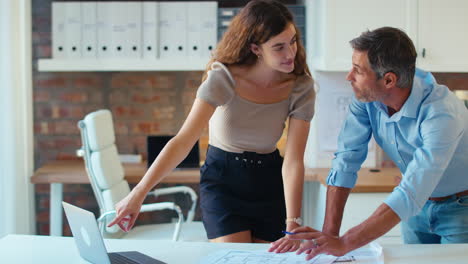 arquitectos masculinos y femeninos con computadoras portátiles se reúnen y discuten planes de construcción en una oficina moderna