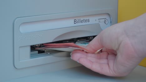 mano tomando billetes de dinero en euros de la ranura del cajero automático, cámara lenta de cerca