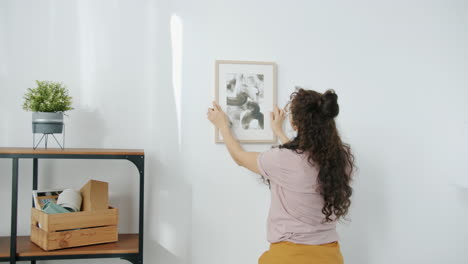 woman hanging a picture on a wall