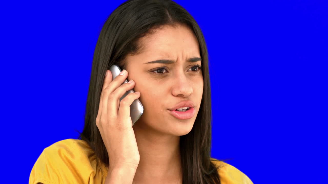 Upset woman talking on the phone on blue screen
