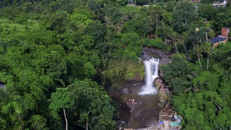 people swimming in the tegenungan waterfall surrounded by green trees in bali, indonesia