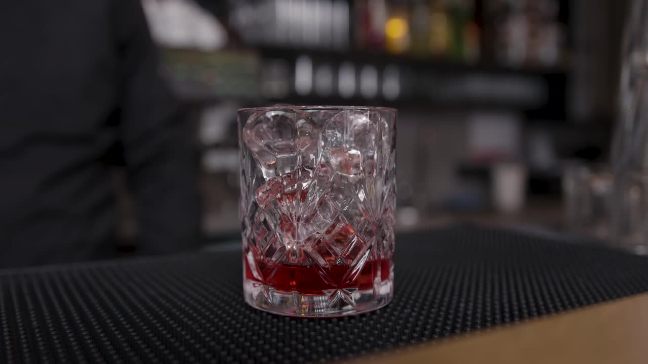 el camarero haciendo un cóctel rojo.