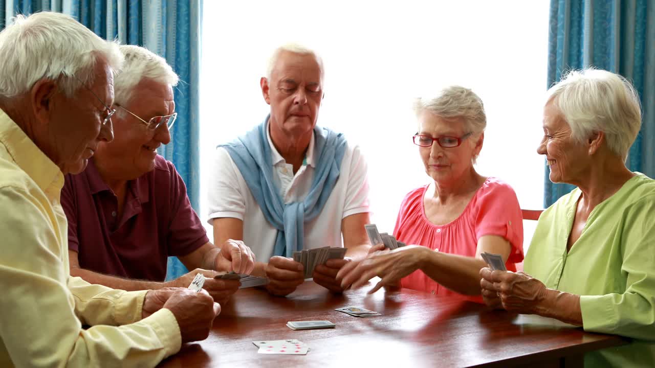 Amigos idosos jogando cartas na sala de estar