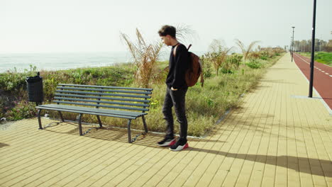 man arriving at the bench near the sea after a walk