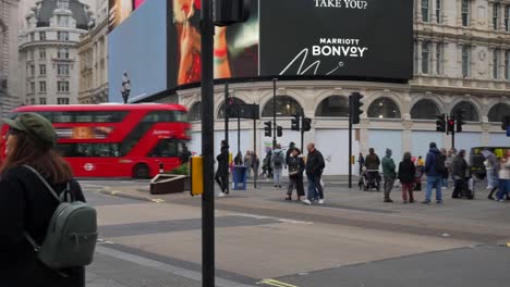 bustling piccadilly circus with iconic red bus, advertising screens, and people walking through london