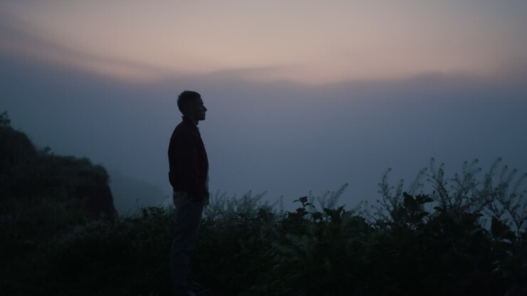 Sad man silhouette standing on mountain top. Lonely guy looking autumn landscape