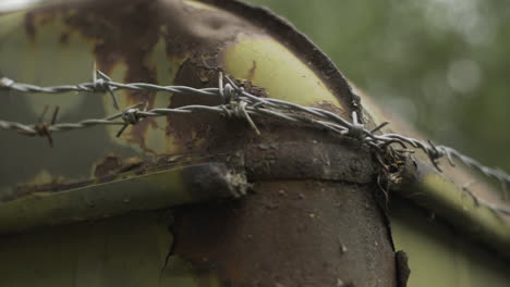 close-up of rusty metal corner lined by barber wire, shallow bokeh