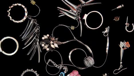 assortment of stylish jewelry including necklaces, rings, bracelets and earrings, creating a glamorous display on a dark background. rotating shot