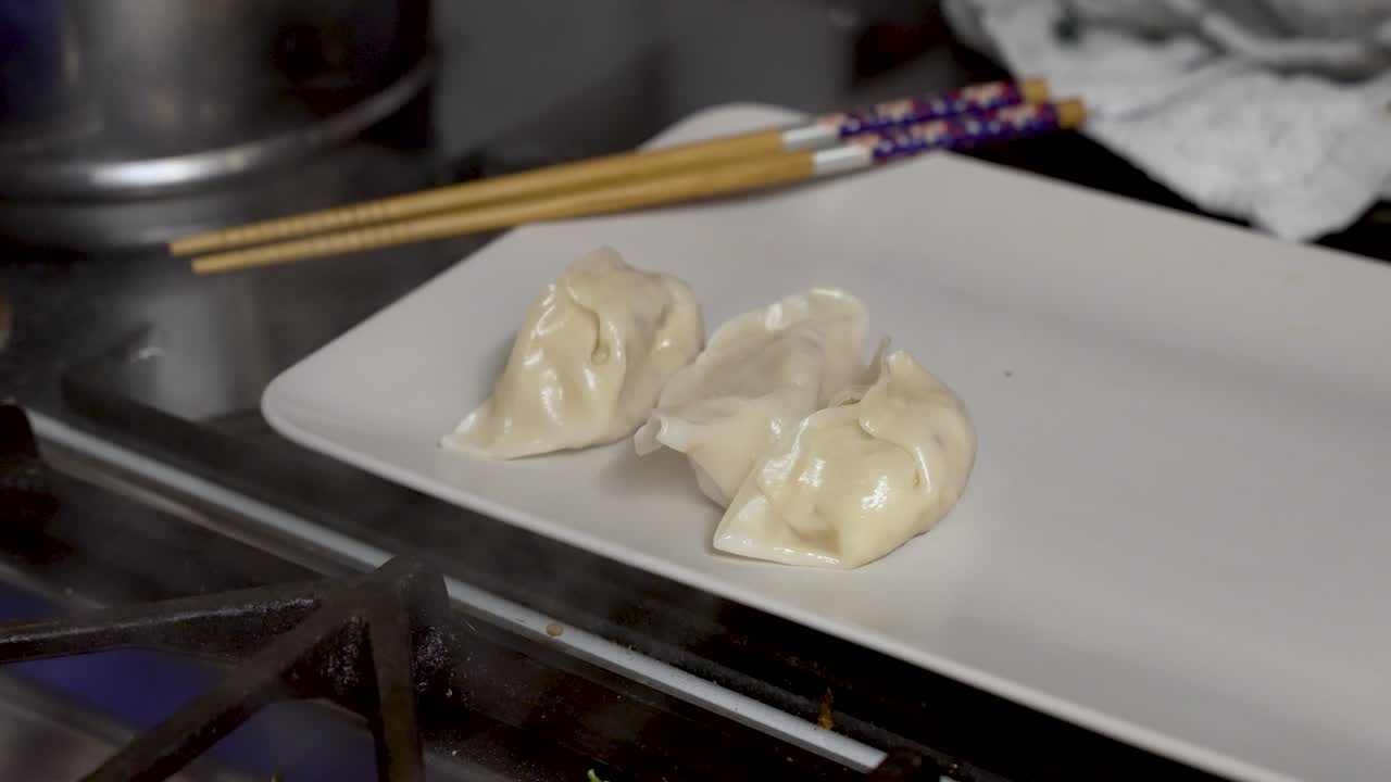 Home chef carefully arranges hot steamy dumplings on a kitchen tray
