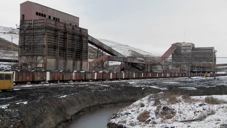 an abandoned mine with ore rail cars in the foreground