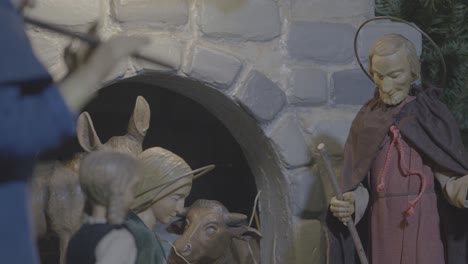 joseph standing in the stable by the crib in a nativity scene