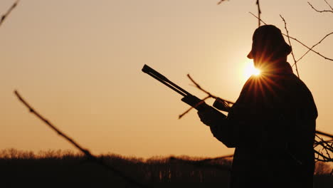 silhouette of a hunter with a gun the sun's rays shine in his face