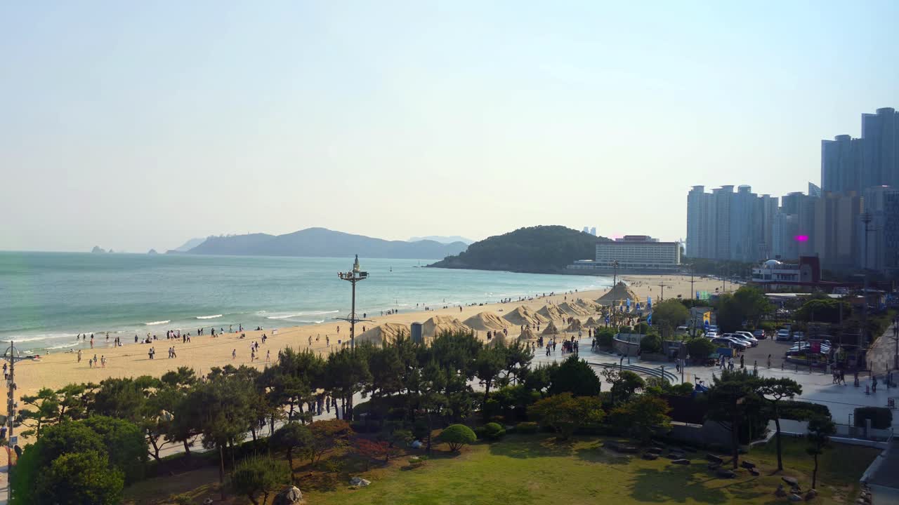 Panoramic view of Haeundae Beach with golden sand, city skyline, and visitors enjoying the seaside in Busan