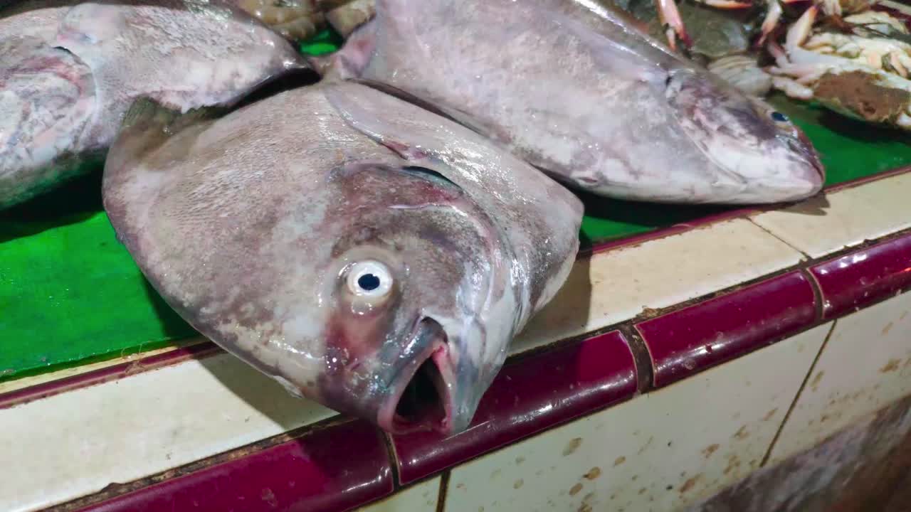 primer plano de pomfret fresco sobre una tapa de cerámica en un mercado de pescado tradicional