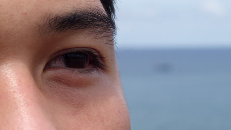 배경에는 바다 바다와 함께 아시아 젊은 검은 어두운 눈의 극단적 인 클로즈업