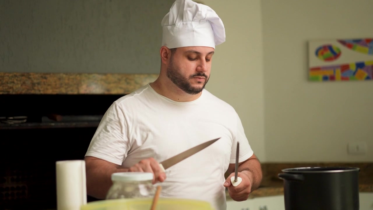 Uno chef professionista utilizza un acciaino su un coltello da cucina.