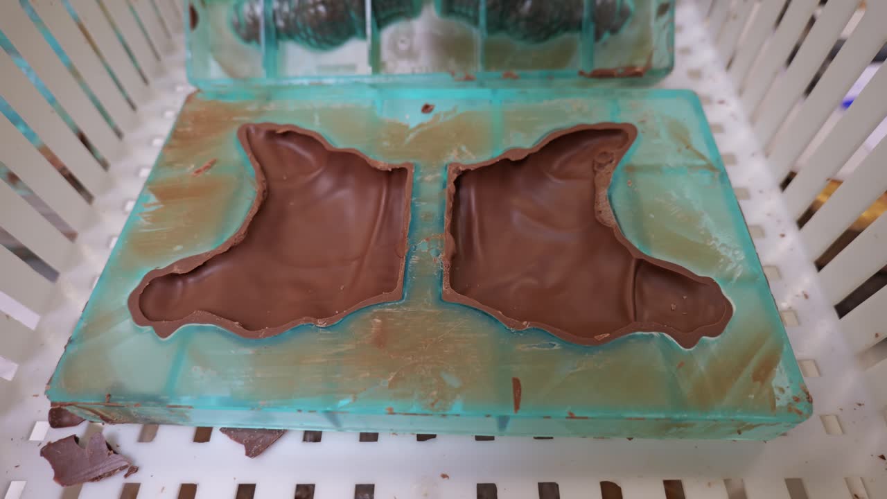 Close-up of a chocolate hen mold being handled during confectionery production