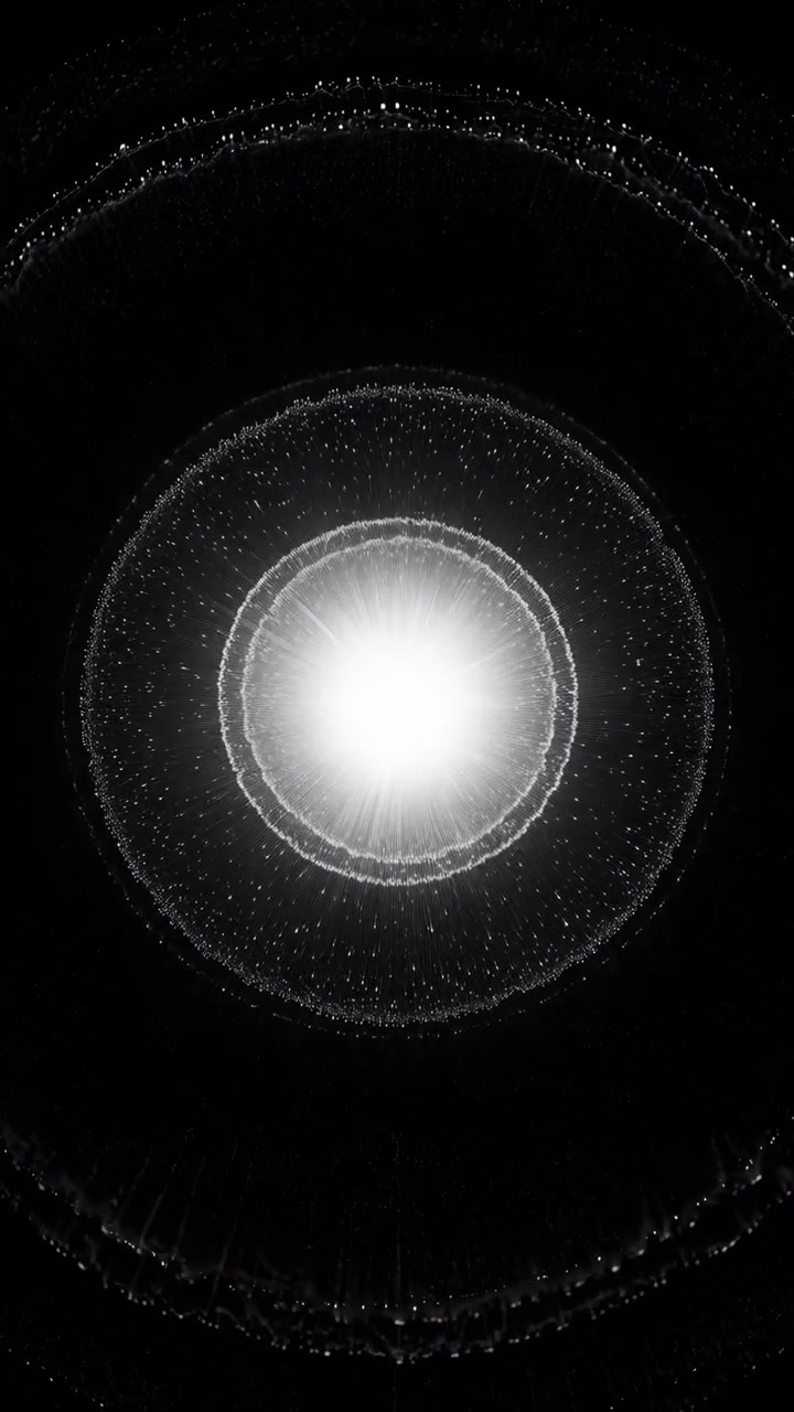 Bandas concéntricas de finas partículas blancas se encogen gradualmente hacia un centro brillante, mientras que los rastros circulares exteriores se desvanecen de la vista a través de una composición vertical oscura y simétrica