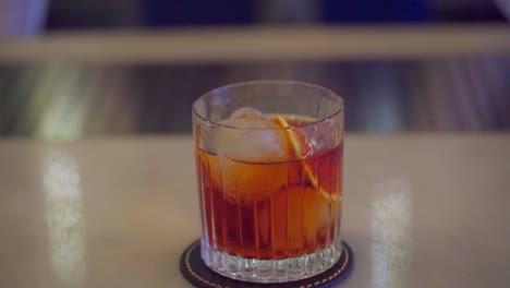 bartender pours a martini with orange and ice