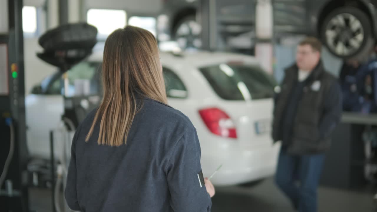 женщина-менеджер обсуждает ремонт автомобиля с механиком в авторемонтной мастерской