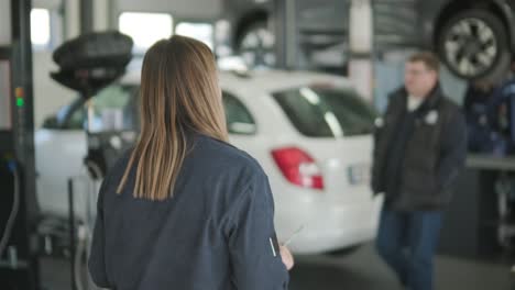 gerente femenina discutiendo la reparación de vehículos con el mecánico en el taller de reparación de automóviles