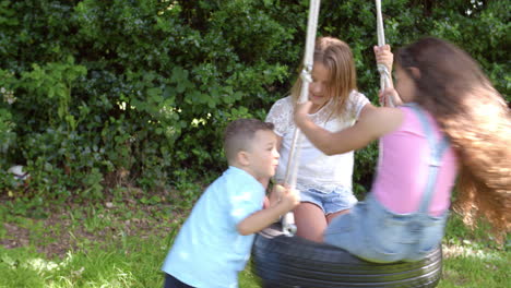 grupo de niños jugando en el columpio de neumáticos en el jardín