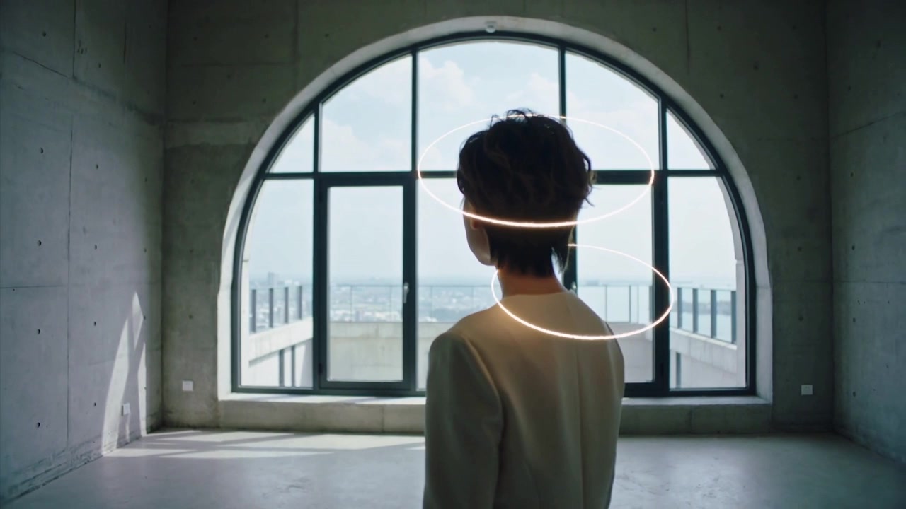 Modella in blazer che si gira, ruotando testa e collo, in un loft con finestre ad arco, mentre una striscia di luce appare per un effetto artistico.