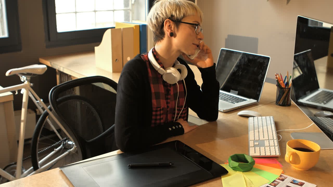 여성 그래픽 디자이너가 휴대전화로 이야기하고 있습니다.