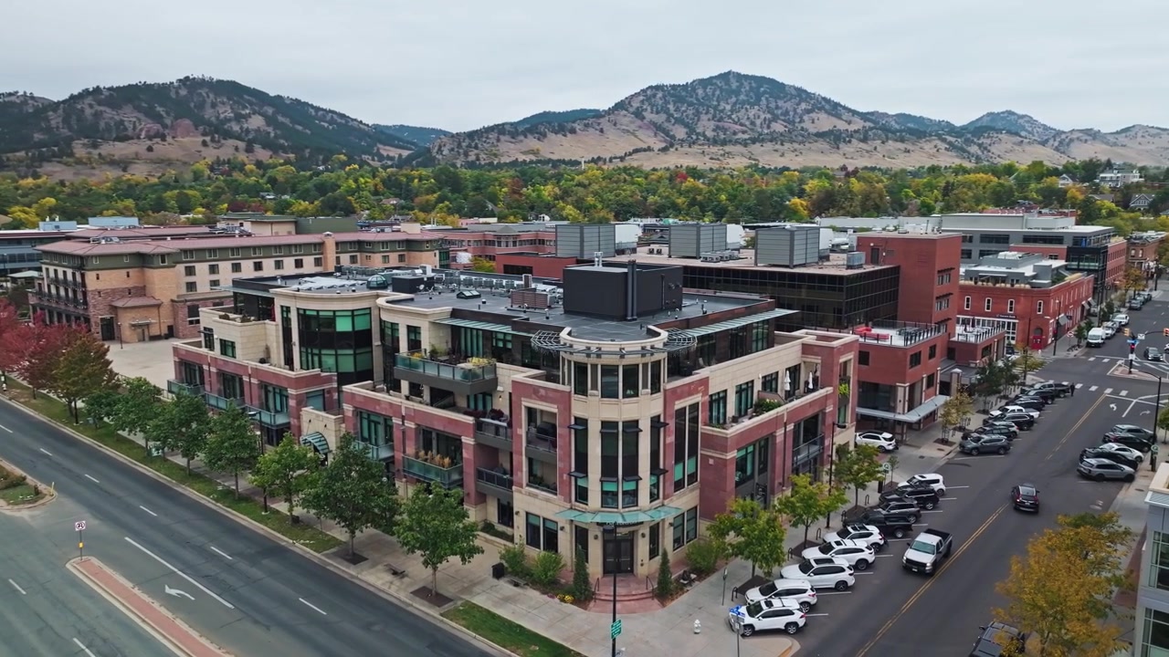 Luftfoto fra bane som etablerer oversikt over Downtown Boulder, Colorado, og viser høstløvverk, forsteder og Flatirons.