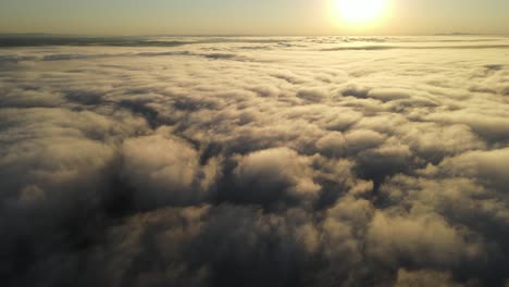 flying over a blanket of clouds at sunrise as if looking out the window of an airplane