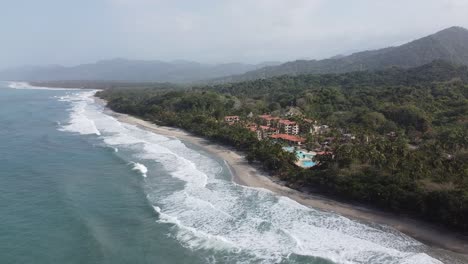 Slow-rotating-aerial-of-beach-resort-reveals-miles-of-empty-hazy-beach