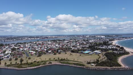 Aerial-view-of-a-coastal-town-and-a-bay-while-boat-passing-by