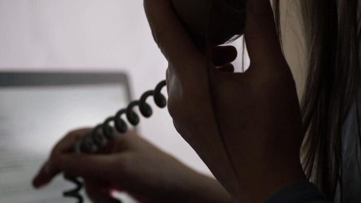 Woman talking on the phone in office in front of laptop close up shot
