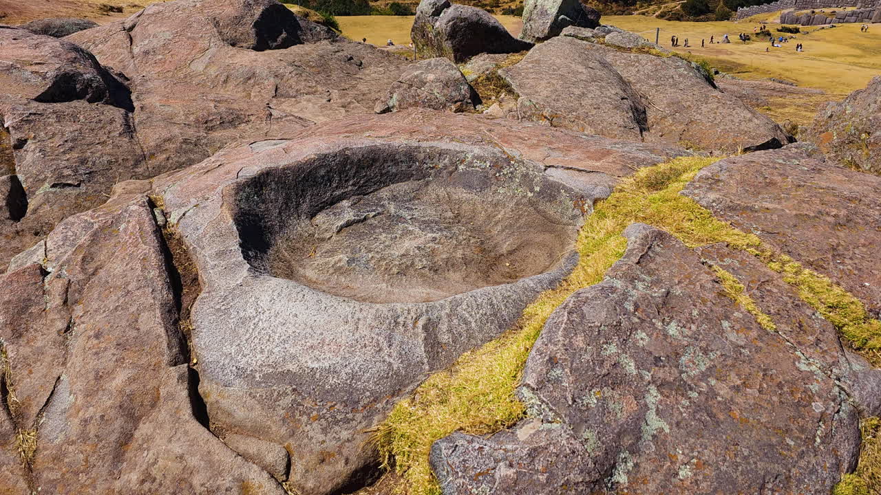 Mortero carved into a large Inca stone at the Saqsaywaman archaeological complex in Cusco. The footage highlights the precision of the ancient stonework and the stone's weathered texture